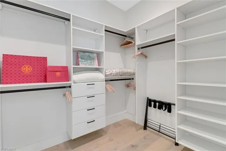 Walk in closet with light hardwood / wood-style floors