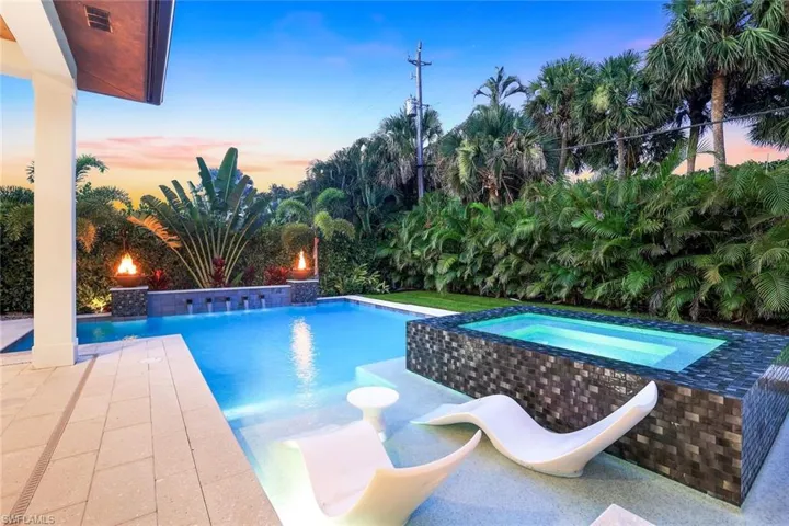 Pool at dusk featuring a patio area and a pool with connected hot tub