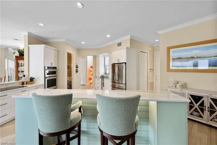 Kitchen with white cabinets, a kitchen island, stainless steel appliances, a breakfast bar, and crown molding