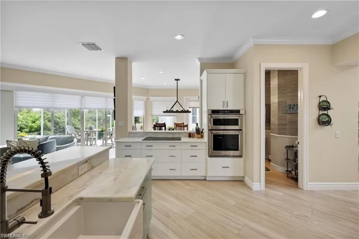 Kitchen with white cabinets, light hardwood / wood-style floors, double oven, and hanging light fixtures