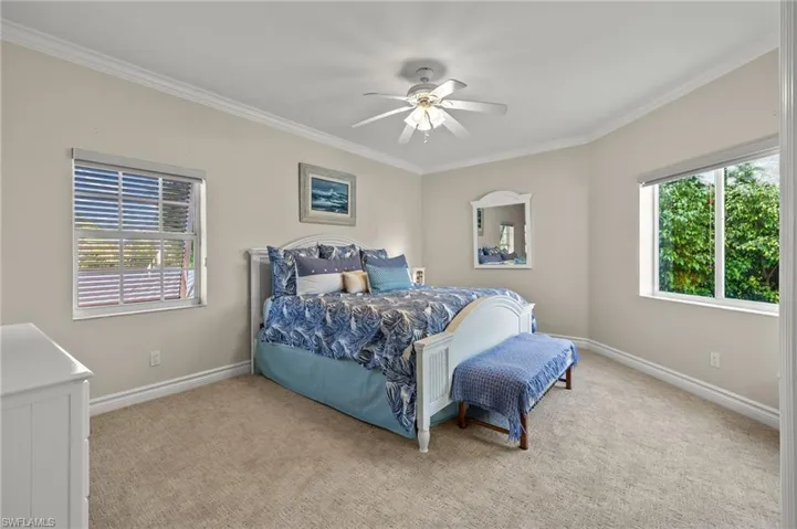 Bedroom with ceiling fan, light carpet, and ornamental molding
