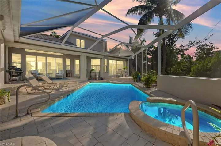 Pool at dusk with a lanai, an in ground hot tub, and a patio area