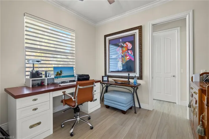 Office space featuring ceiling fan, light wood-type flooring, and crown molding