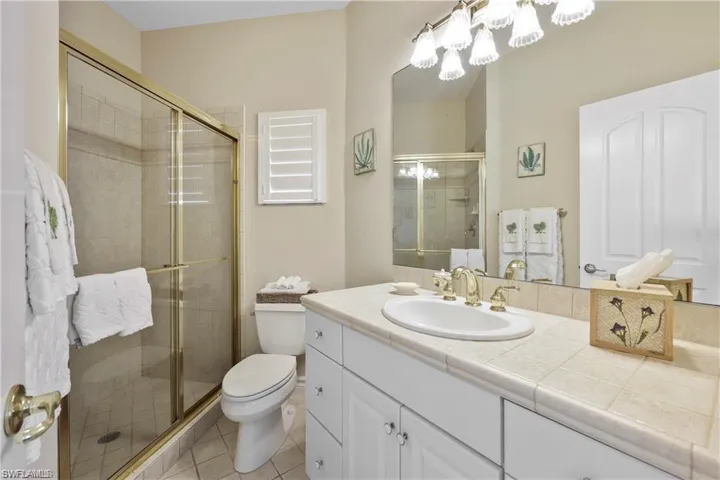 Bathroom with vanity, toilet, tile patterned floors, and a shower with door