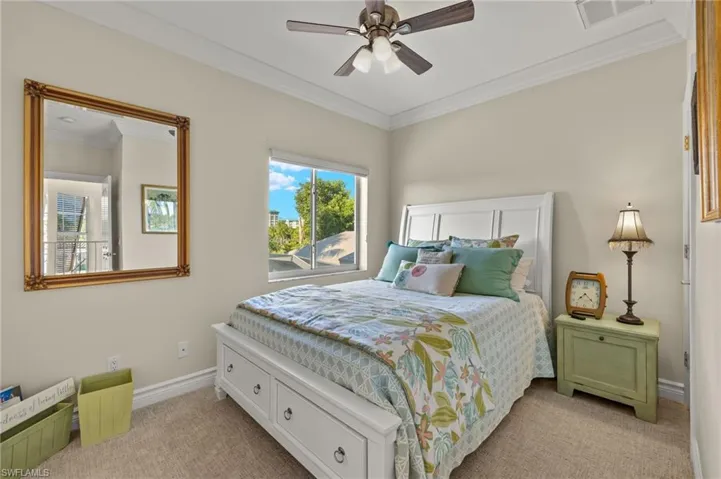 Bedroom with ceiling fan, light carpet, and ornamental molding