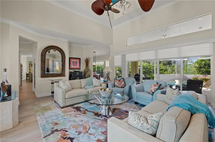 Living room with ornamental molding, a towering ceiling, light hardwood / wood-style floors, and ceiling fan