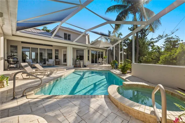 View of swimming pool featuring glass enclosure, area for grilling, an in ground hot tub, and a patio area