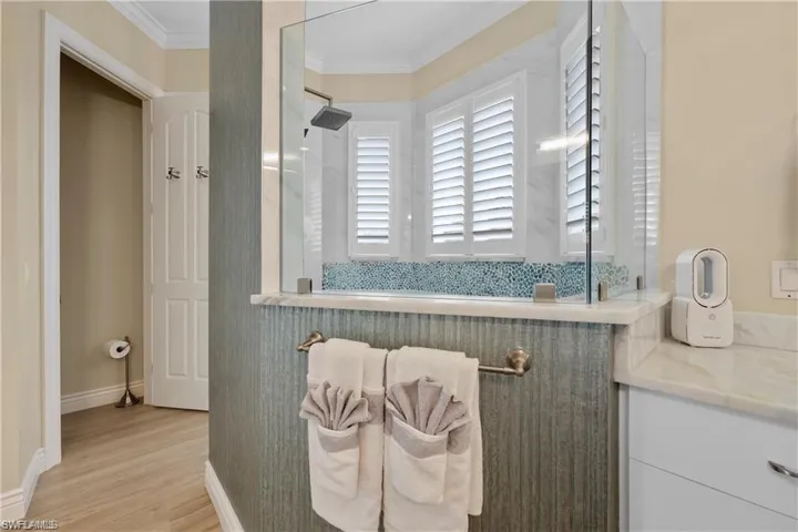 Bathroom featuring vanity, an enclosed shower, hardwood / wood-style floors, and crown molding