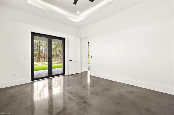 Spare room with concrete flooring, a tray ceiling, baseboards, and ceiling fan