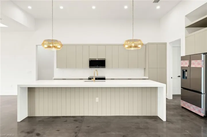 Kitchen featuring finished concrete flooring, appliances with stainless steel finishes, a notable chandelier, and modern cabinets