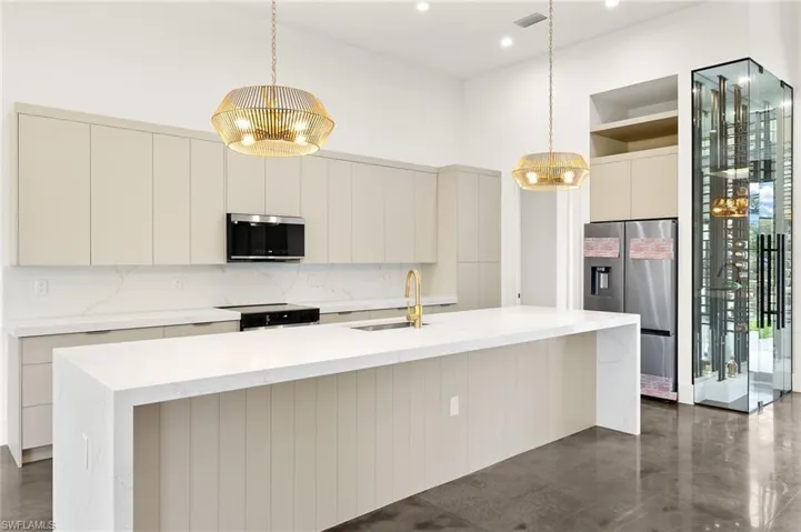 Kitchen with appliances with stainless steel finishes, an inviting chandelier, a sink, and modern cabinets