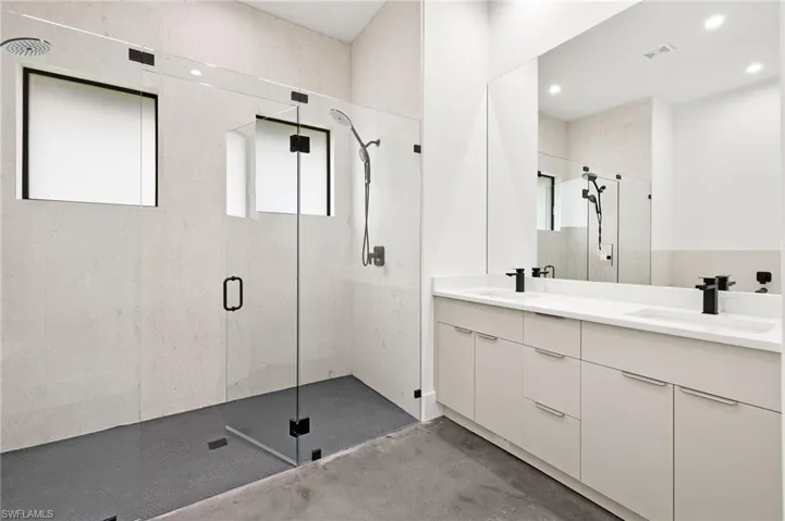 Bathroom featuring double vanity, a sink, and a stall shower