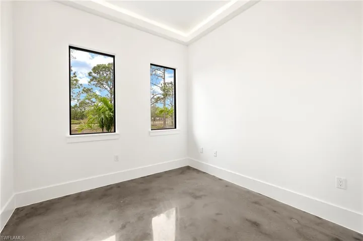 Unfurnished room featuring a tray ceiling, concrete floors, and baseboards