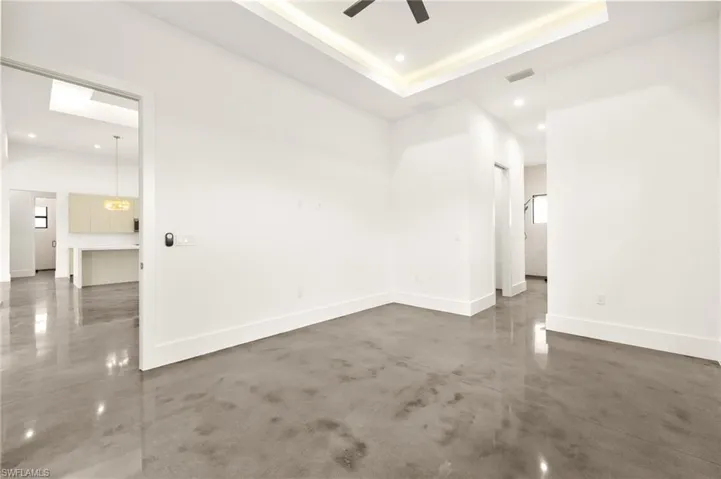 Empty room featuring baseboards, a ceiling fan, finished concrete floors, and a raised ceiling