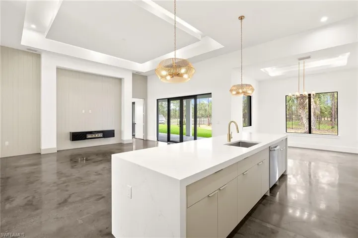 Kitchen with pendant lighting, a chandelier, a sink, light countertops, and a raised ceiling