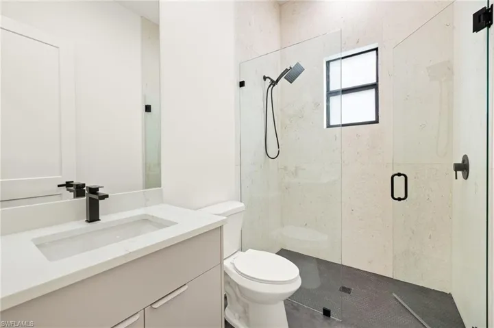 Full bath with toilet, vanity, and a stall shower