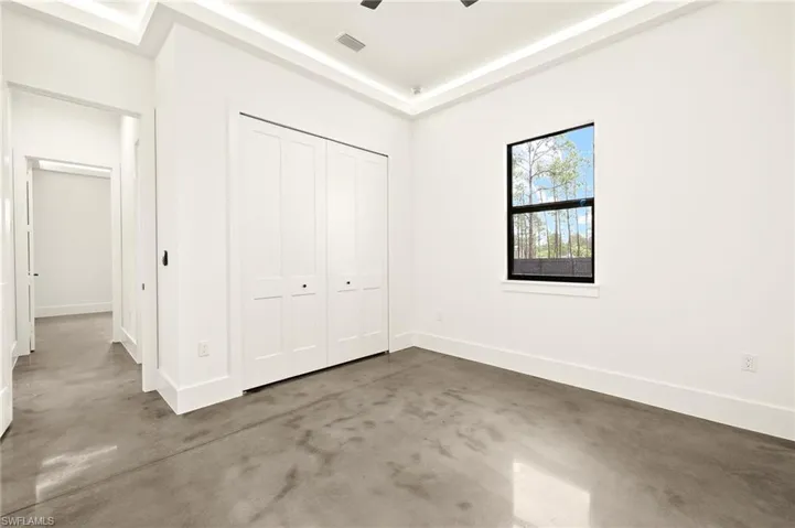 Unfurnished bedroom with a closet, baseboards, and finished concrete floors