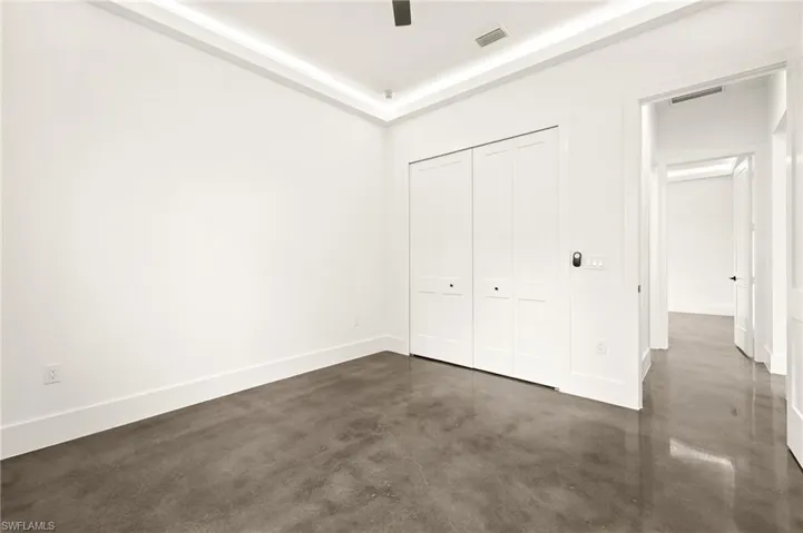 Unfurnished bedroom with concrete flooring, visible vents, baseboards, and a closet