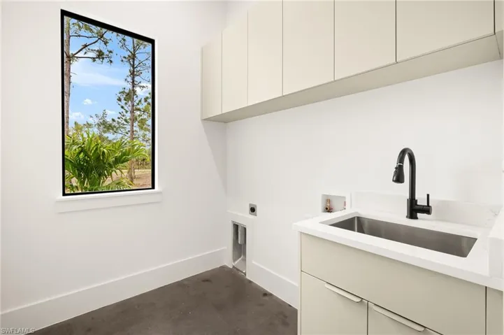 Laundry room with hookup for a washing machine, hookup for an electric dryer, a sink, baseboards, and cabinet space