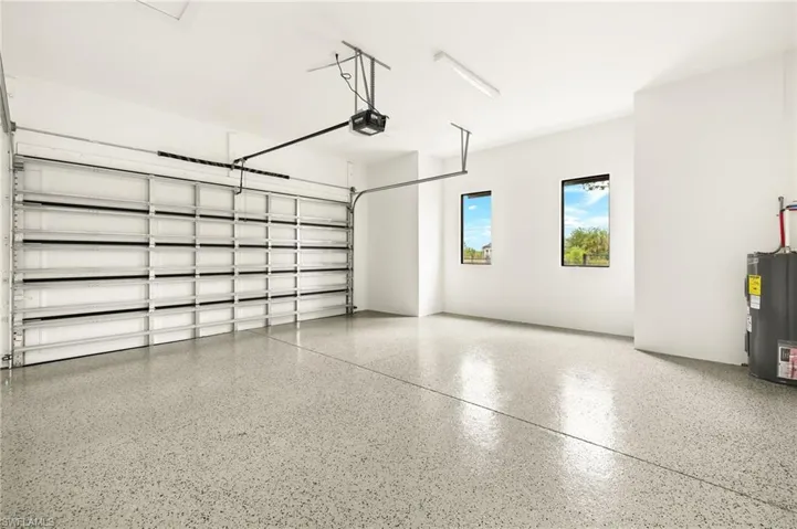 Garage featuring electric water heater and a garage door opener