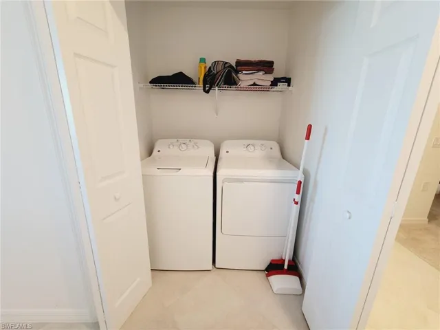 Laundry room with washer and clothes dryer and light tile patterned flooring