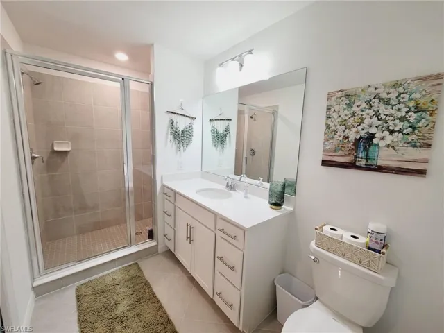 Bathroom featuring tile patterned flooring, vanity, toilet, and a shower with door