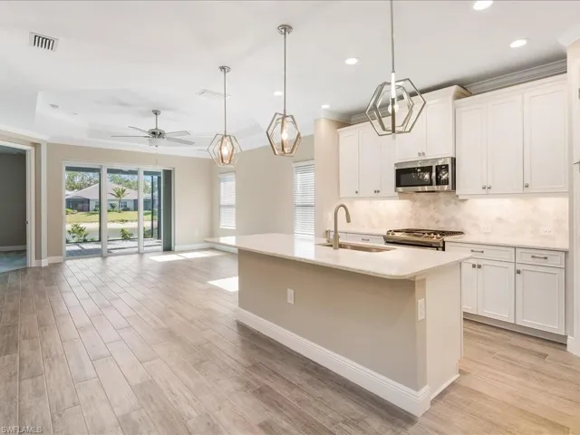 Open concept living area featuring wood-finish flooring, a tray ceiling, and a ceiling fan