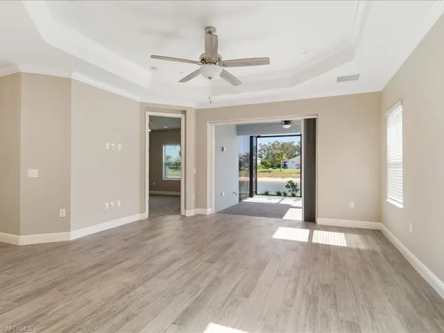 Tray ceiling with crown molding, wood-finish flooring, ceiling fan, and large sliding glass door