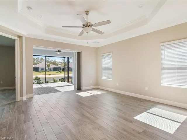Tray ceiling with recessed lighting, wood-finish flooring, multiple windows with blinds, and sliding glass doors to a screened patio