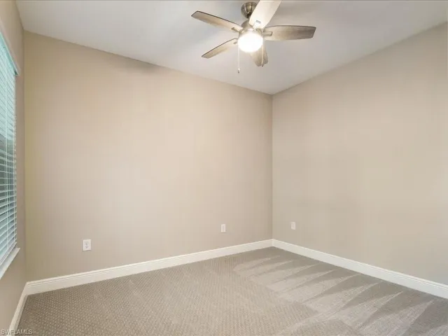 Vaulted ceiling, ceiling fan with integrated lighting, window with blinds, light tan wall color, and carpet flooring