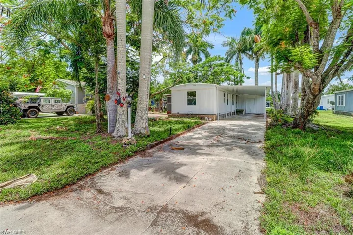 Manufactured / mobile home with driveway, an attached carport, and a front lawn