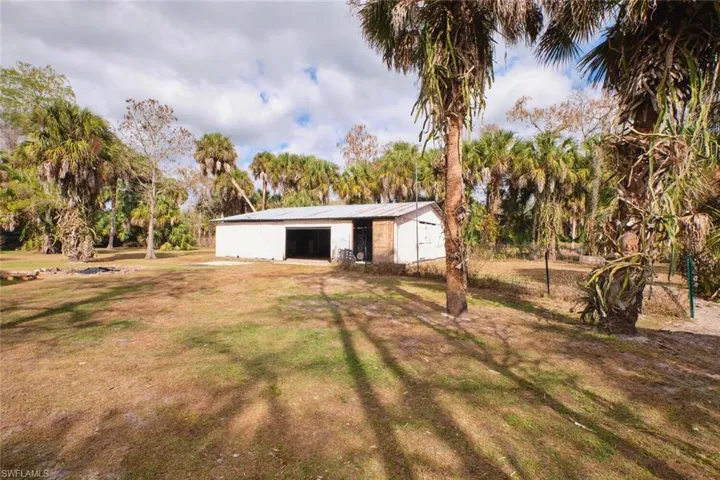 View of green lawn featuring an outbuilding, a detached barn, and view of wooded area