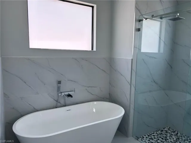 Bathroom with shower with separate bathtub and tile walls