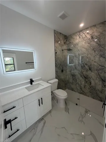Modern bathroom featuring a glass-enclosed shower with dark marble-style wall tiling and a built-in niche