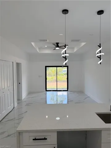 Open-concept interior featuring bright white walls, large format tile flooring, and a sliding glass door