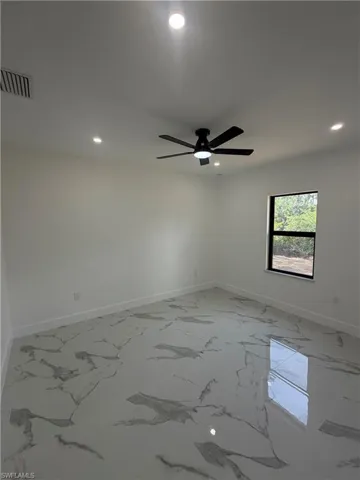 Spacious room featuring large format tile flooring, a black ceiling fan with an integrated light, and recessed lighting