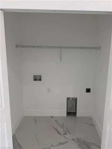 Utility room featuring a wire shelving unit, dedicated washer and dryer hookups, and white and gray marble-look flooring