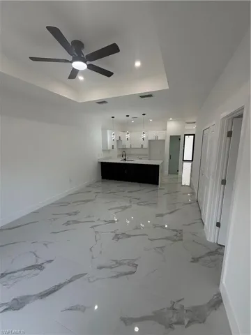 Open-concept living space featuring high ceilings with a modern ceiling fan, recessed lighting, and large format marble-look tile flooring