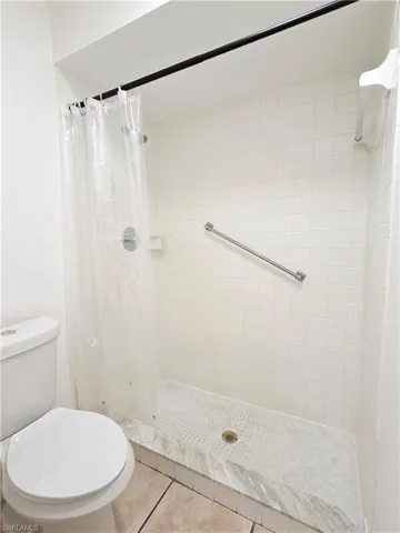 Bathroom with a shower stall and light tile patterned floors