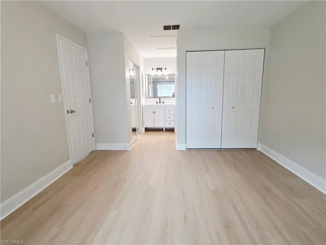 Unfurnished bedroom featuring a closet, light wood-type flooring, and ensuite bathroom