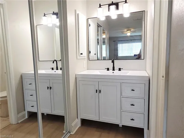 Bathroom featuring light wood-type flooring, two vanities, and ceiling fan