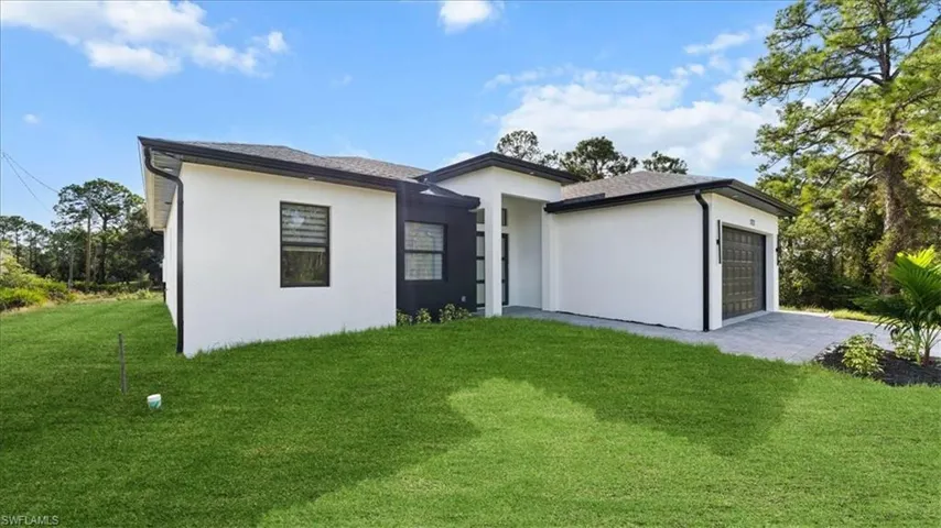 View of front of home featuring a garage, a front lawn, stucco siding, and driveway
