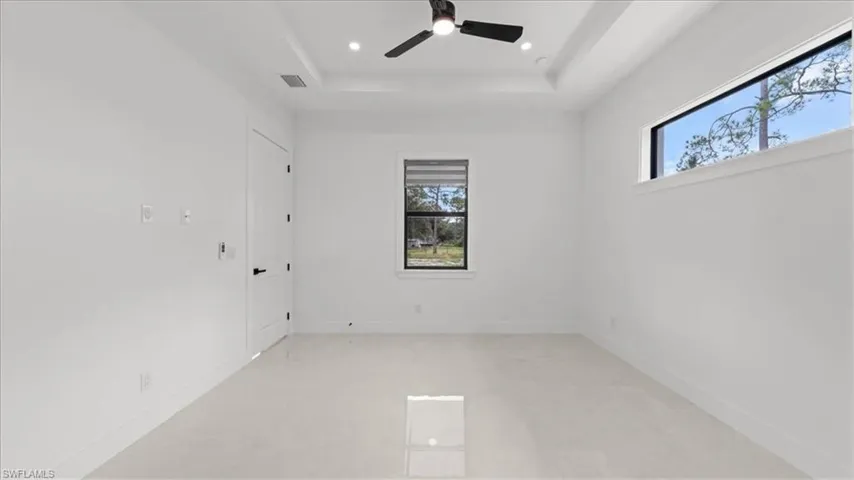 Spare room with a tray ceiling, ceiling fan, and recessed lighting