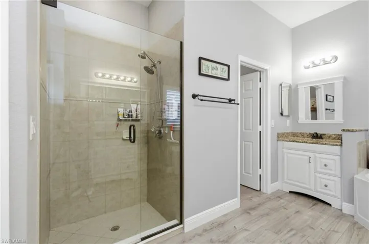 Full bath with vanity, a shower stall, and light wood-type flooring