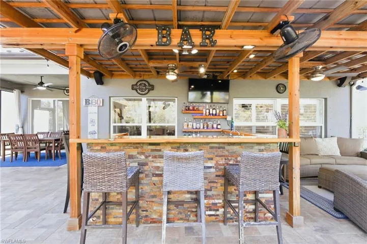 Indoor bar with healthy amount of natural light, stone finish floors, and ceiling fan