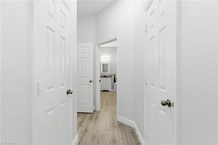 Corridor with light wood finished floors and a textured wall