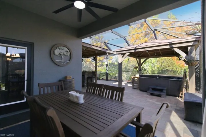 View of patio / terrace with a hot tub, a lanai, a ceiling fan, a sunroom, and outdoor dining area