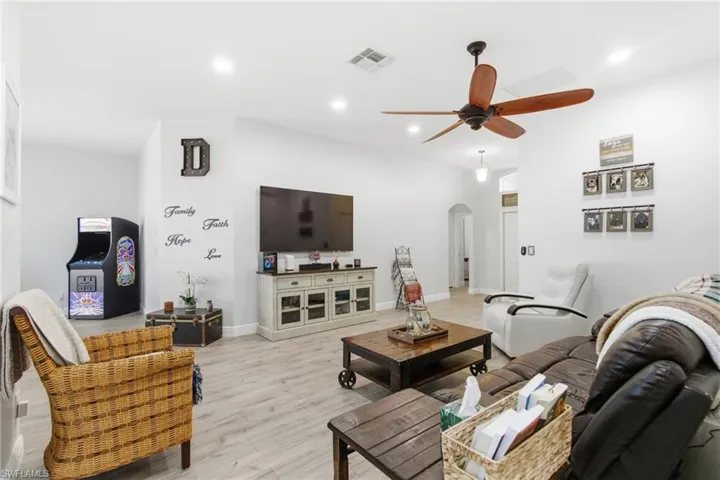 Living area with arched walkways, ceiling fan, recessed lighting, and light wood finished floors