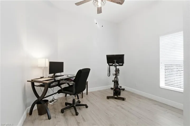Office area with light wood-style floors and ceiling fan