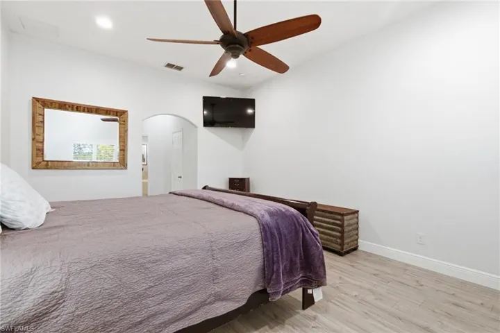 Bedroom with wood finished floors, a ceiling fan, and arched walkways